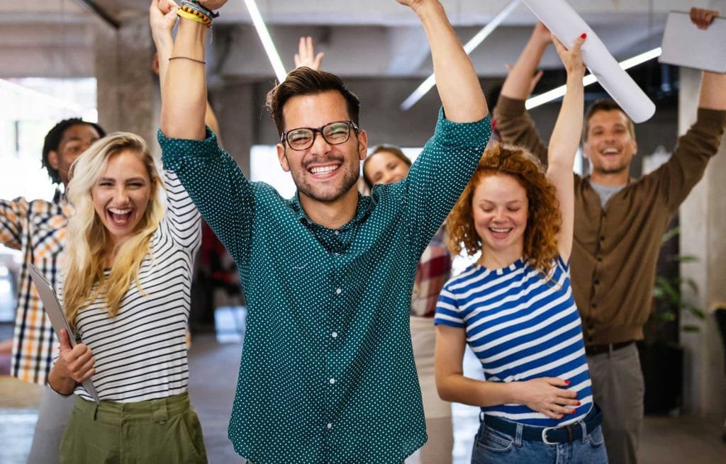 photo of cheerful office workers raising their arms smiling